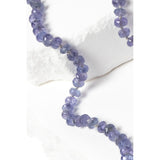 Close-up of faceted tanzanite rondelle gemstones showing luminous blue and lavender tones with subtle gray undertones, individually knotted to enhance movement and durability