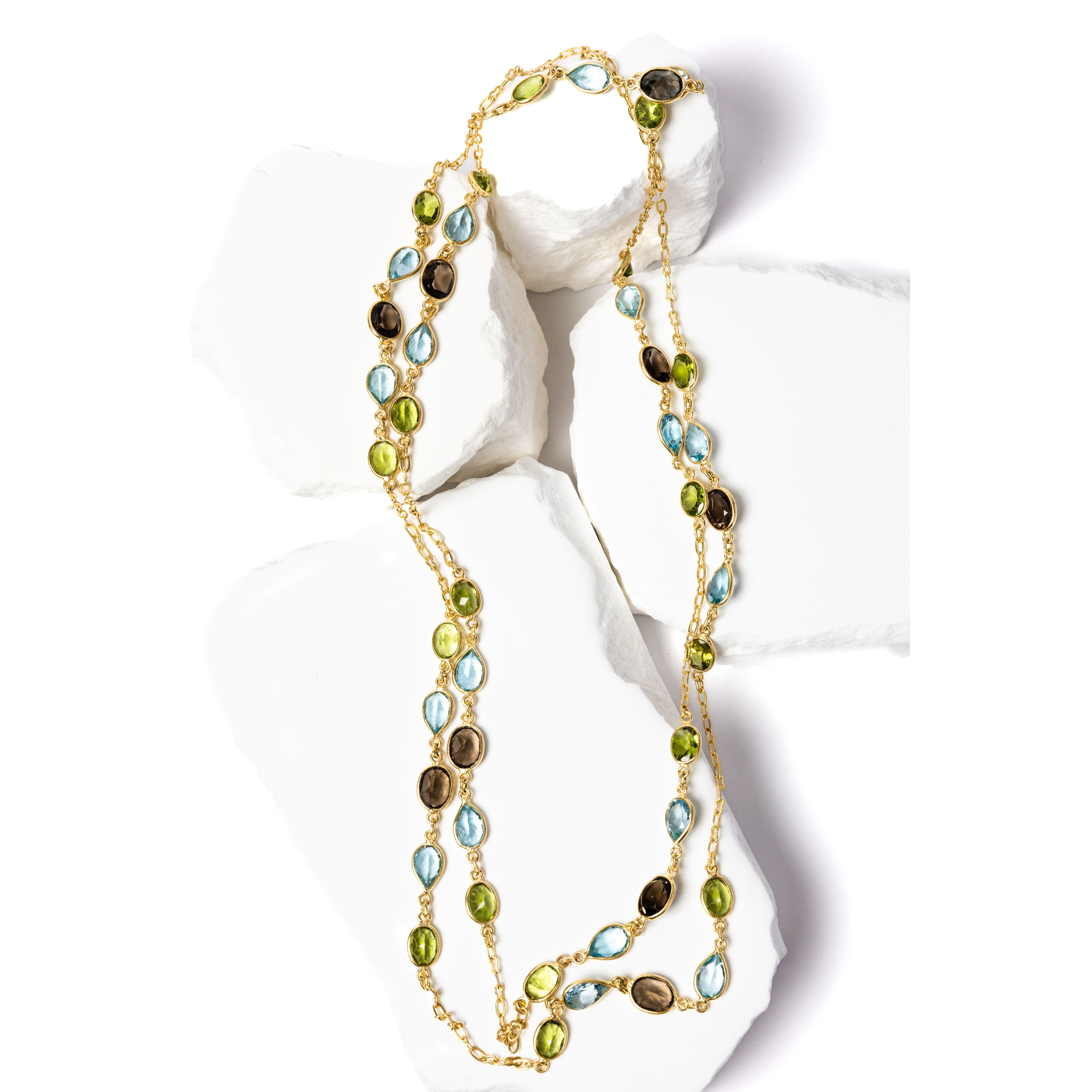 Rare Harmony gold station necklace featuring smoky quartz, blue topaz, and peridot gemstones arranged along a fine chain, creating a balanced, fluid composition of color and light.