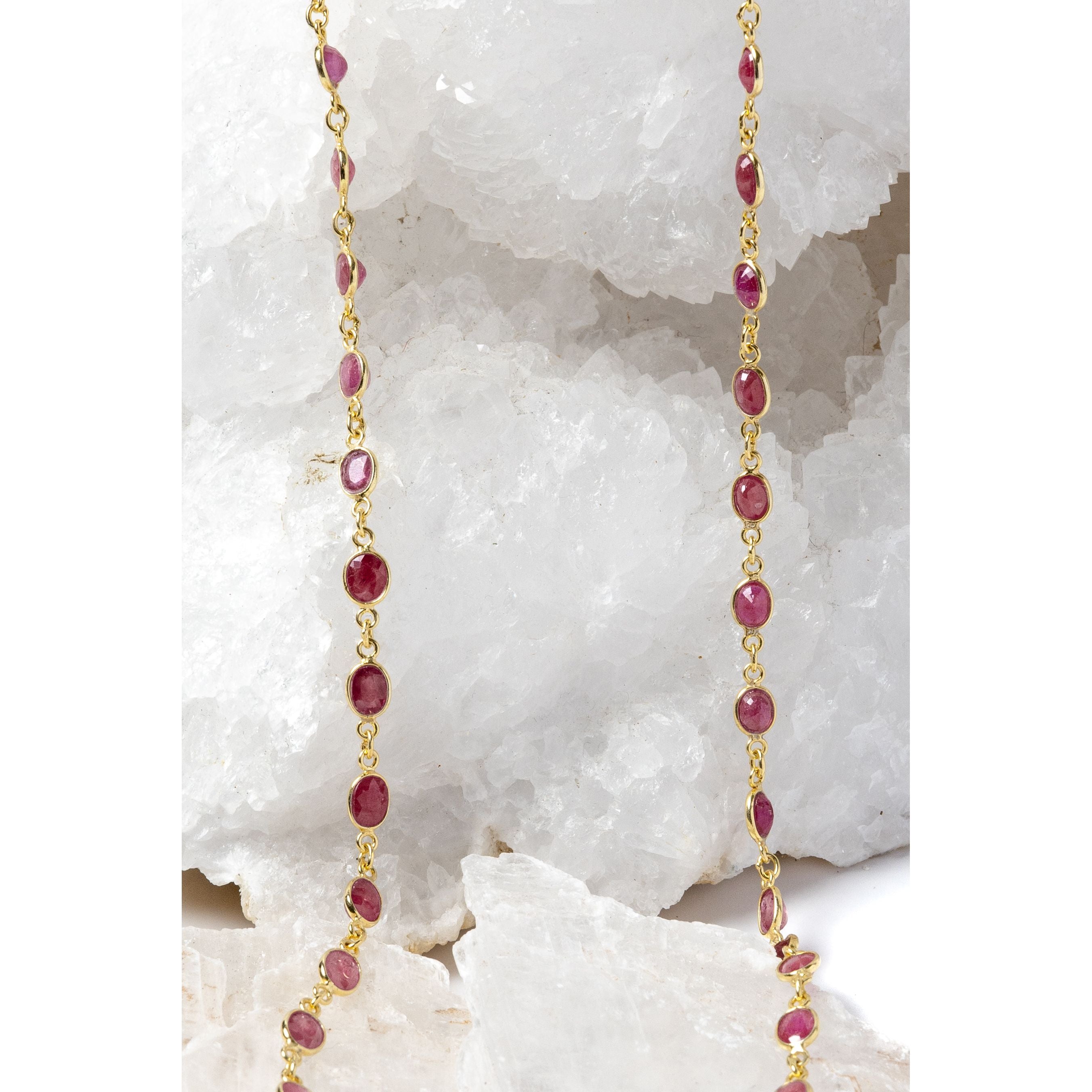 Gold station necklace featuring cherry-colored rubies, shown in its full length with a fluid, elegant drape.
