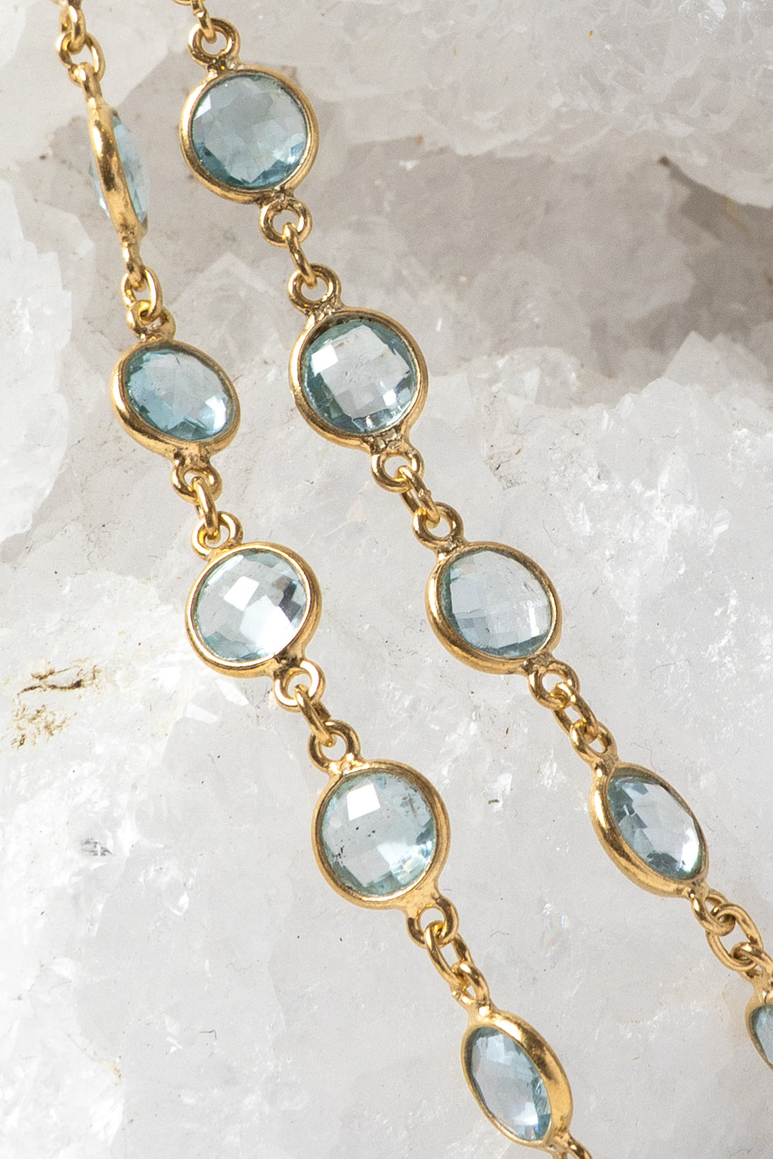 Close-up of the Soft Tide necklace showing blue topaz stones in bezel settings along a fine gold chain.