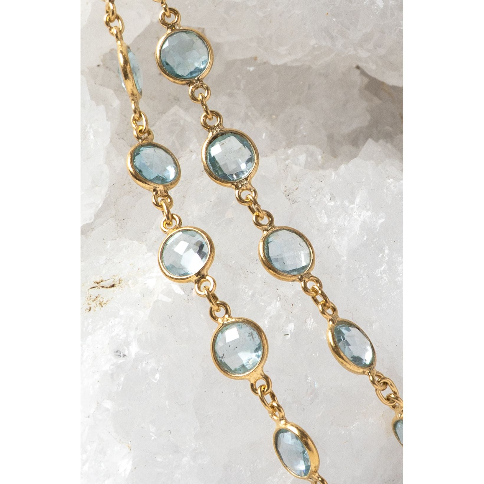 Close-up of the Soft Tide necklace showing blue topaz stones in bezel settings along a fine gold chain.
