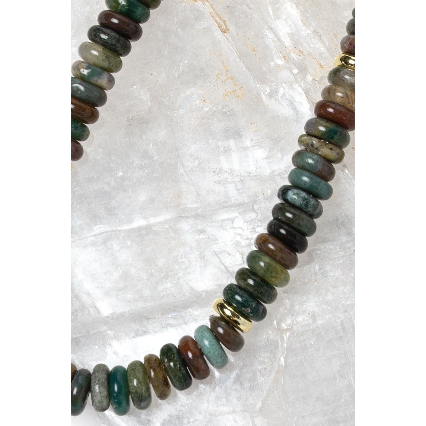 Close-up detail of polished multicolor gemstone rondelles featuring rich green, teal, brown, olive, and smoky natural tones with gold accent spacers.