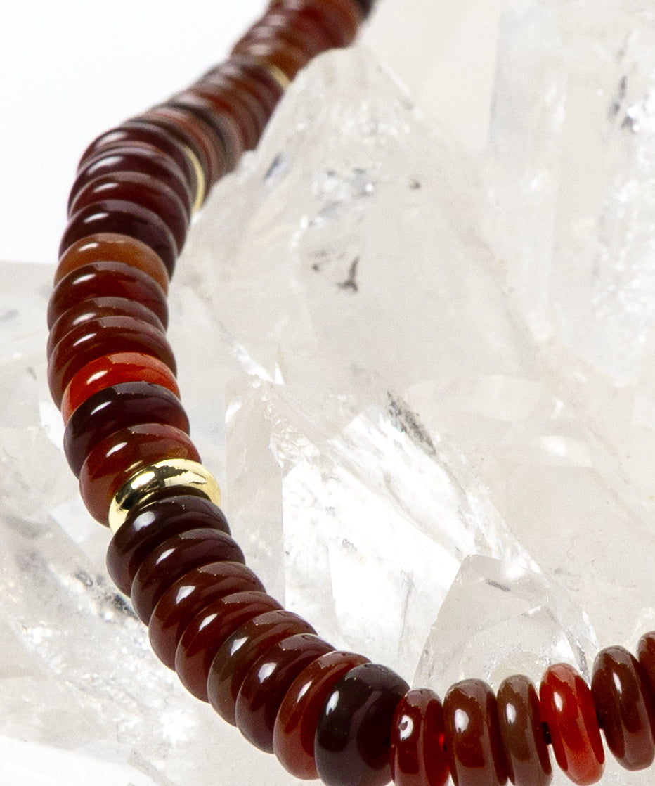 Close-up detail of polished red agate rondelles showcasing warm terracotta, cinnamon, and deep crimson tones accented by luminous gold-plated spacers.