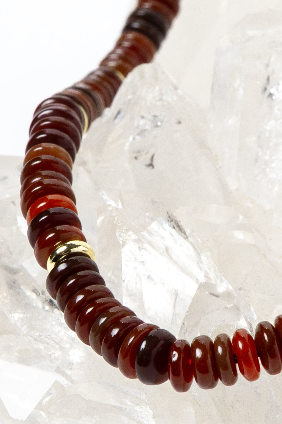 Close-up detail of polished red agate rondelles showcasing warm terracotta, cinnamon, and deep crimson tones accented by luminous gold-plated spacers.