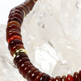 Close-up detail of polished red agate rondelles showcasing warm terracotta, cinnamon, and deep crimson tones accented by luminous gold-plated spacers.