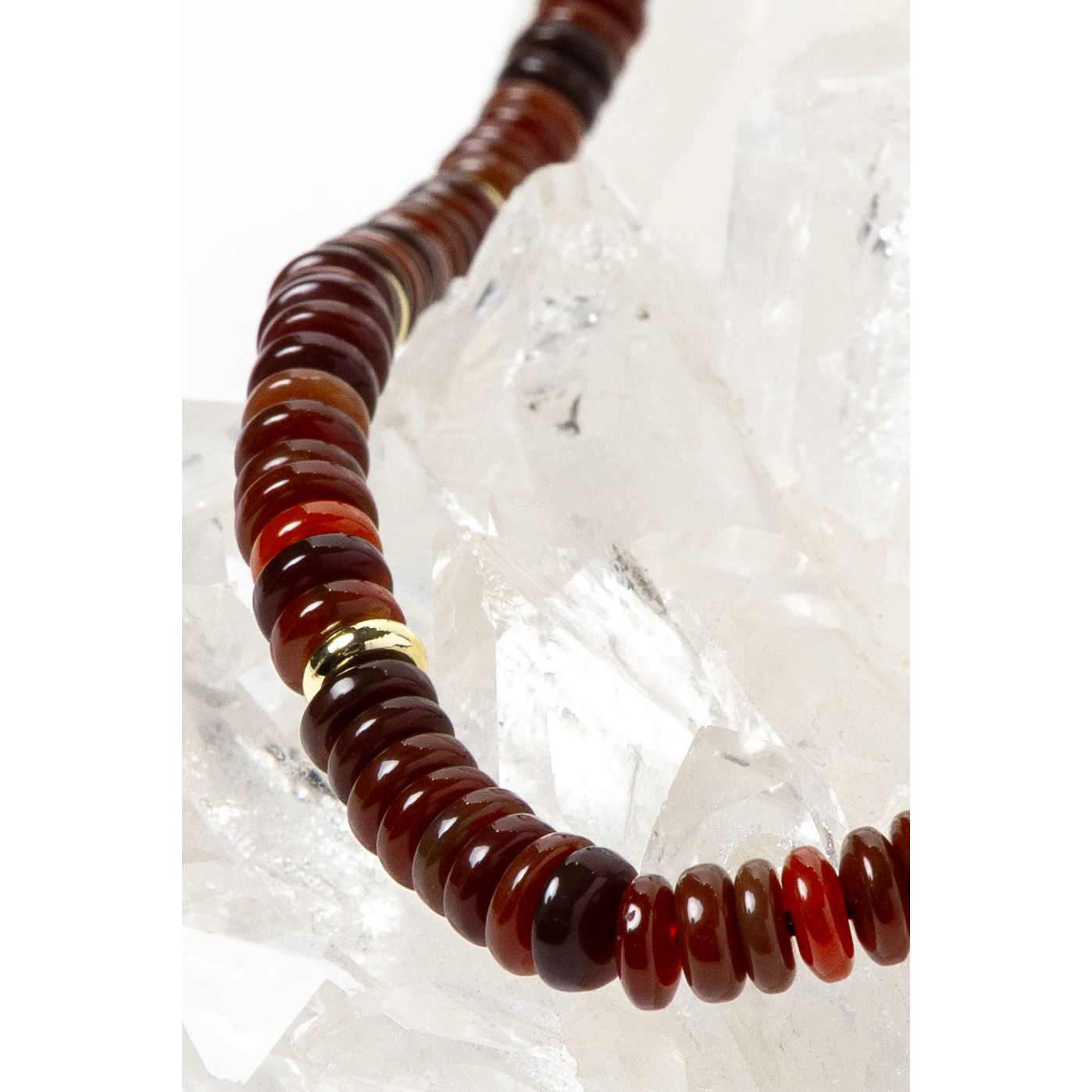 Close-up detail of polished red agate rondelles showcasing warm terracotta, cinnamon, and deep crimson tones accented by luminous gold-plated spacers.