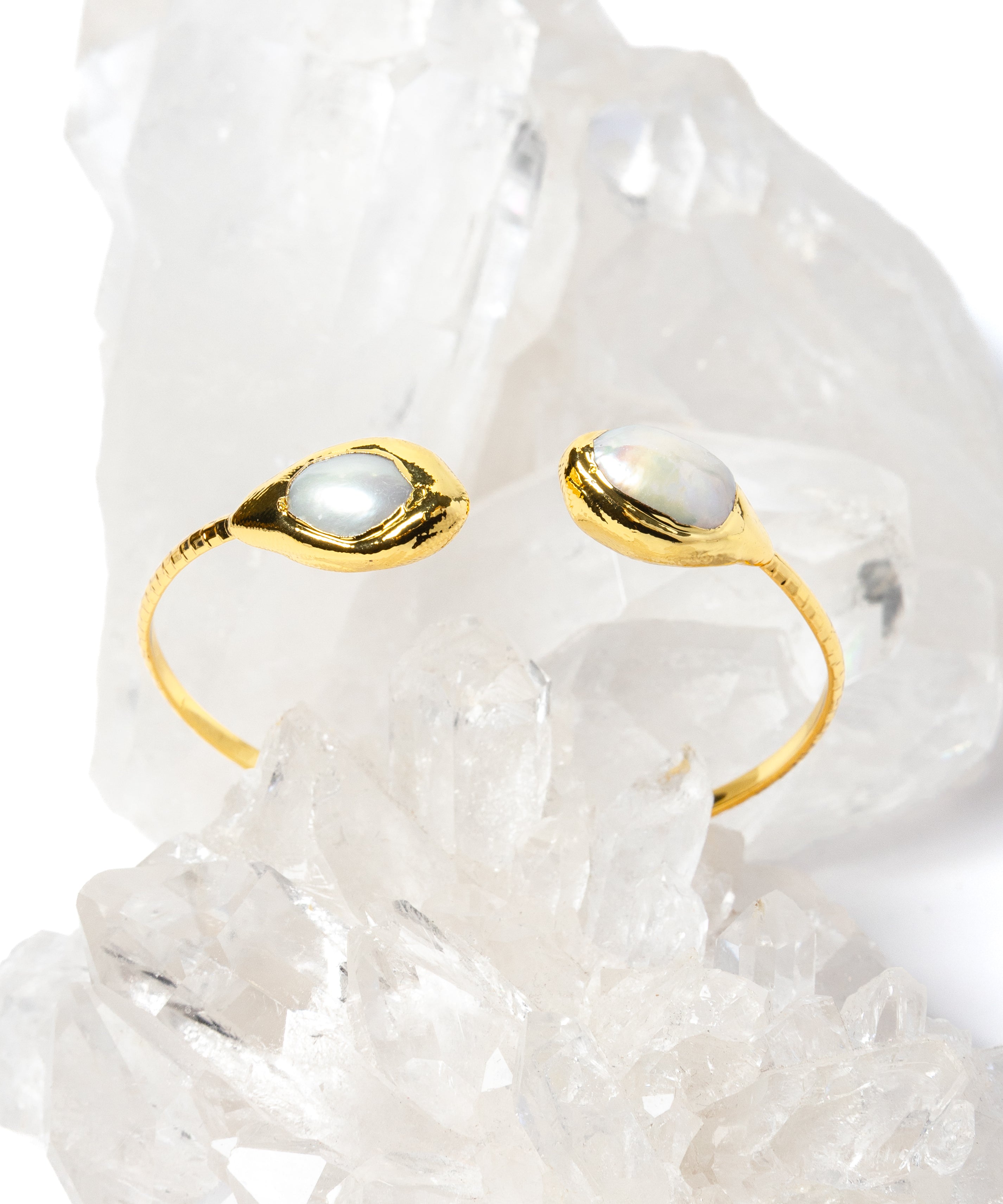 Luxury open cuff bracelet featuring two luminous natural baroque pearls set in polished gold-plated bezels with a refined sculptural silhouette.