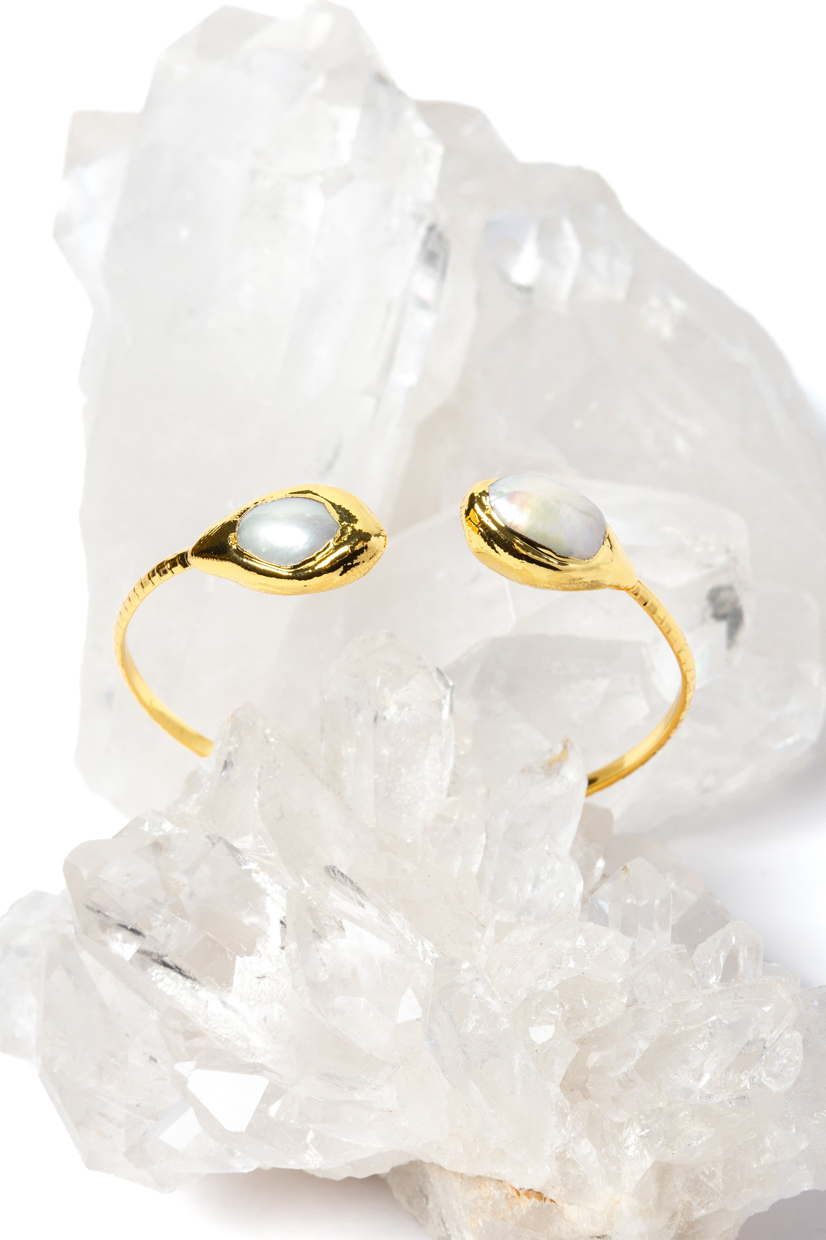 Luxury open cuff bracelet featuring two luminous natural baroque pearls set in polished gold-plated bezels with a refined sculptural silhouette.