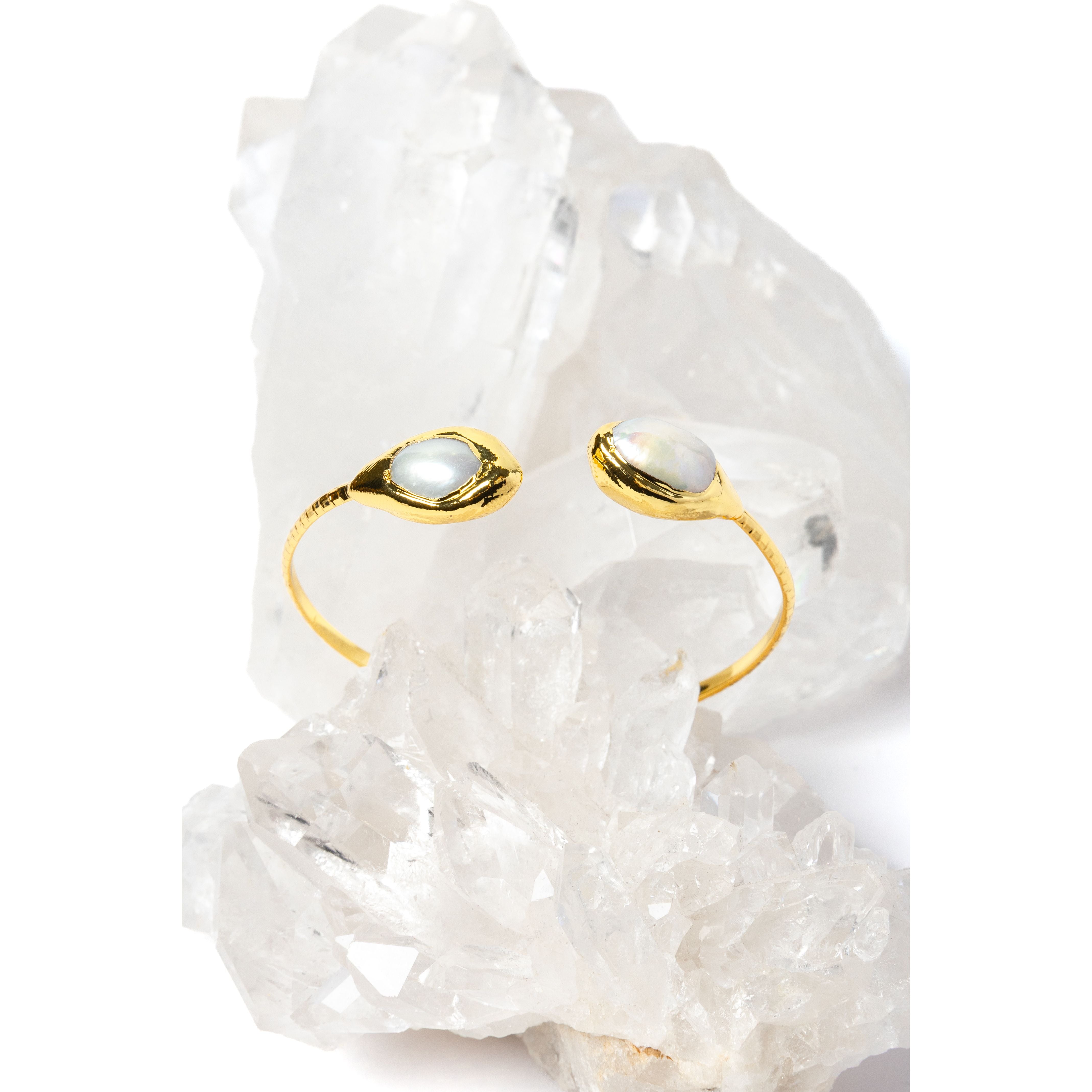 Luxury open cuff bracelet featuring two luminous natural baroque pearls set in polished gold-plated bezels with a refined sculptural silhouette.