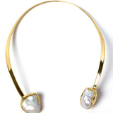 Luxury sculptural open-front collar necklace featuring two substantial natural baroque pearls suspended from a polished gold-plated curved structure with a refined contemporary silhouette.