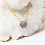 Close-up of a flat, polished abalone pendant with natural mauve, sage-green and pearl-gray iridescence.