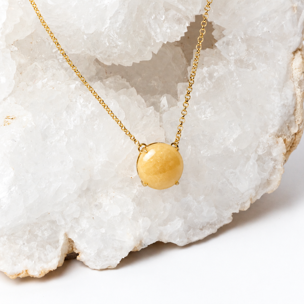 Close-up of a polished honey-yellow aragonite cabochon with subtle natural matrix in an 18k gold-plated setting.