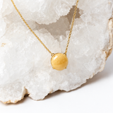 Close-up of a polished honey-yellow aragonite cabochon with subtle natural matrix in an 18k gold-plated setting.