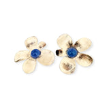 Romantic floral earrings featuring brushed gold-plated petals surrounding polished blue onyx cabochons in a soft sculptural flower design.