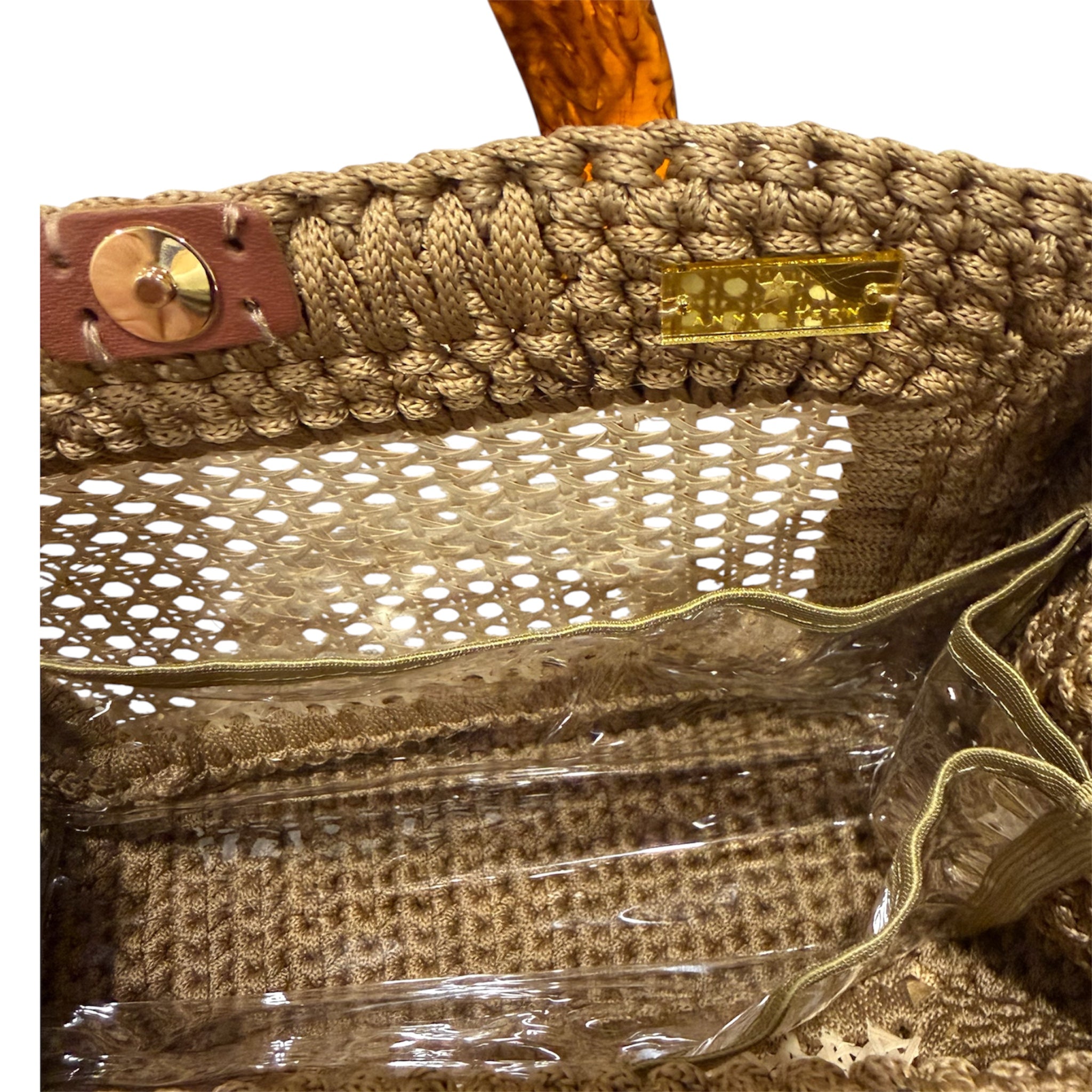 Interior view of the Amélie · Sandstone handbag featuring a dimensional caramel crochet frame, woven rattan center structure, gold-tone hardware, magnetic closure, and discreet transparent insert pocket within the unlined sculptural silhouette.
