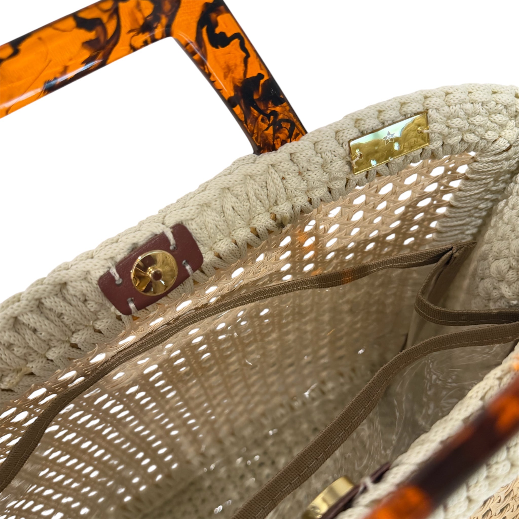 Interior view of the Amélie · Coastal Breeze handbag featuring an architectural woven rattan center, richly textured off-white crochet frame, gold-tone hardware, magnetic closure, and discreet transparent insert pocket within an airy unlined sculptural silhouette.