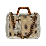 Off-white handcrafted luxury handbag featuring an architectural woven rattan center, richly textured crochet frame, sculptural marbled resin handles, statement resin chain strap, and elongated tassel detail with an airy open silhouette and elevated natural textures.