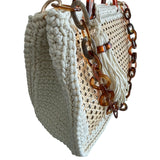 Side view of the Amélie · Coastal Breeze handbag featuring a richly textured off-white crochet frame, architectural woven rattan center panels, sculptural marbled resin handles, statement resin chain strap, and elongated tassel detail with dimensional handcrafted construction and airy open silhouette.