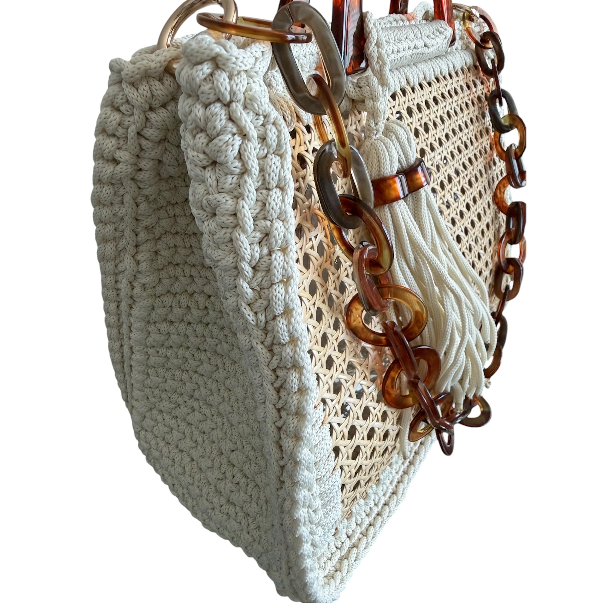 Side view of the Amélie · Coastal Breeze handbag featuring a richly textured off-white crochet frame, architectural woven rattan center panels, sculptural marbled resin handles, statement resin chain strap, and elongated tassel detail with dimensional handcrafted construction and airy open silhouette.