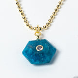 Close-up of a natural Apatite gemstone pendant showcasing vivid ocean-blue tones, faceted geometric shape, cubic zirconia detail, and gold-plated setting.