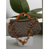 Hand-crocheted Paloma handbag in an earthy wood-toned hue with subtle green undertones and dimensional textured stitching, featuring a marbled amber resin top handle and a coordinating chain strap.