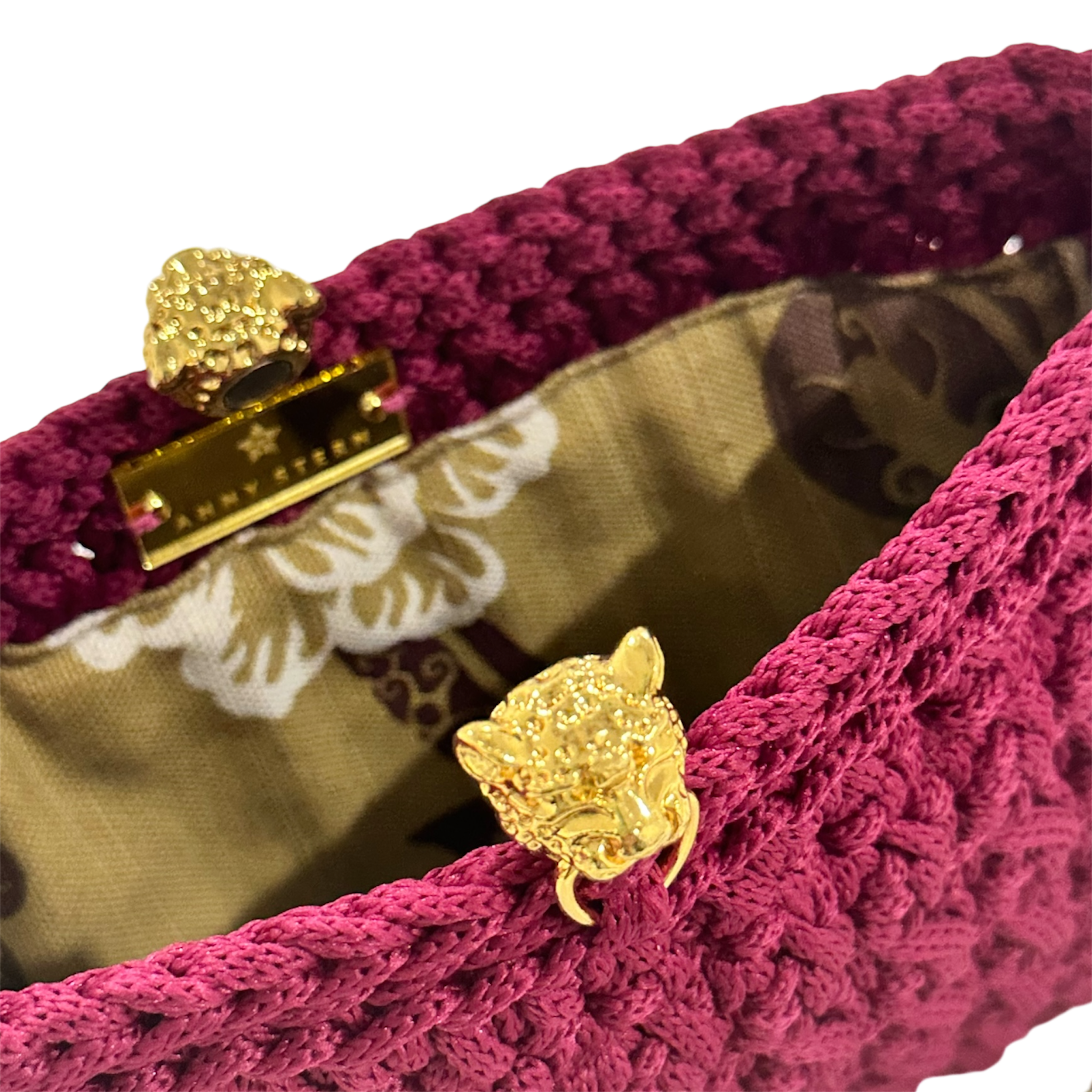 Interior of the Bertha Clutch Berry Epoch featuring a gold-tone tiger clasp, botanical lining, magnetic closure, and hand-crocheted construction.