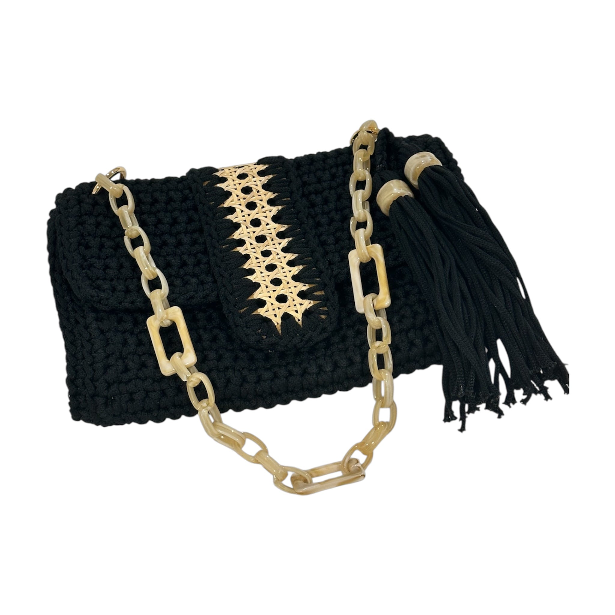 Hand-crocheted black Camille clutch featuring richly textured stitching, a refined handwoven cane panel along the flap, a luminous resin chain handle, and a sculptural tassel accent finished with polished resin rings—Butterfly Island edition.