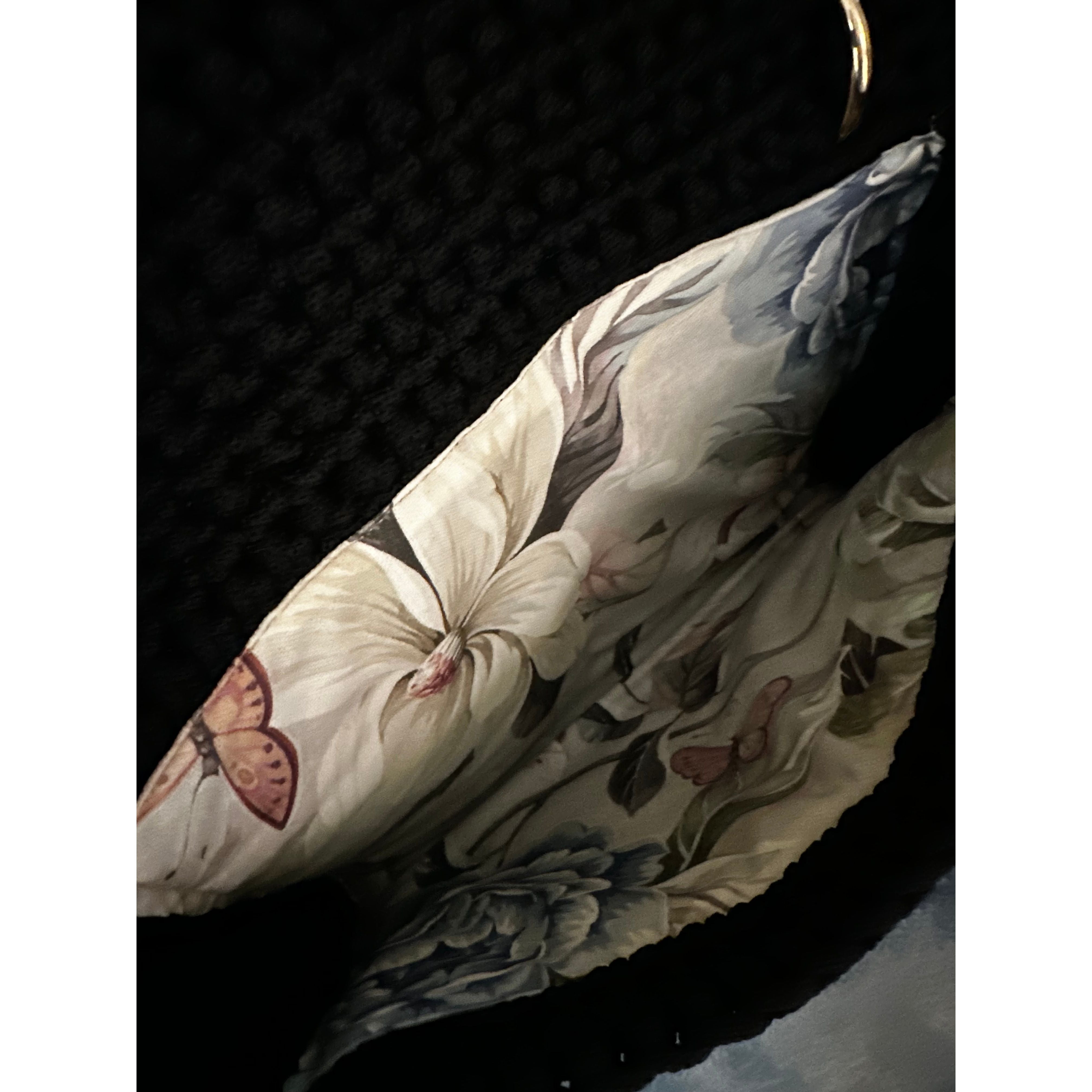 Interior of the Camille clutch revealing a softly structured silhouette lined in an elegant floral textile with delicate butterfly accents, echoing the Butterfly Island motif.
