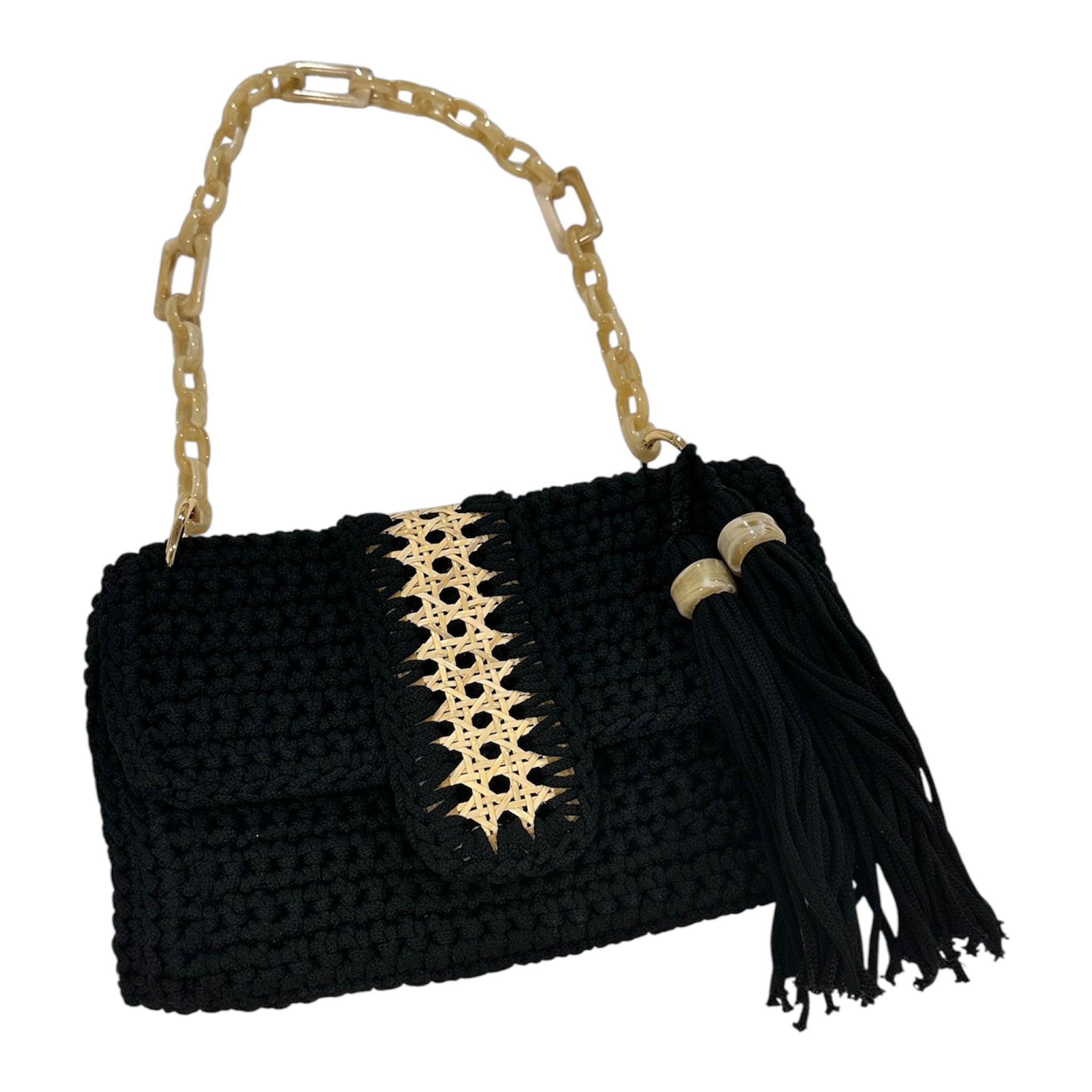 Hand-crocheted black Camille clutch featuring richly textured stitching, a refined handwoven cane panel along the flap, a luminous resin chain handle, and a tassel accent finished with polished resin rings.