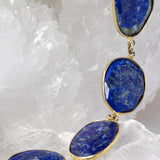 Close-up of faceted lapis lazuli gemstones showcasing rich royal-blue color, natural pyrite inclusions, and vermeil bezel settings.