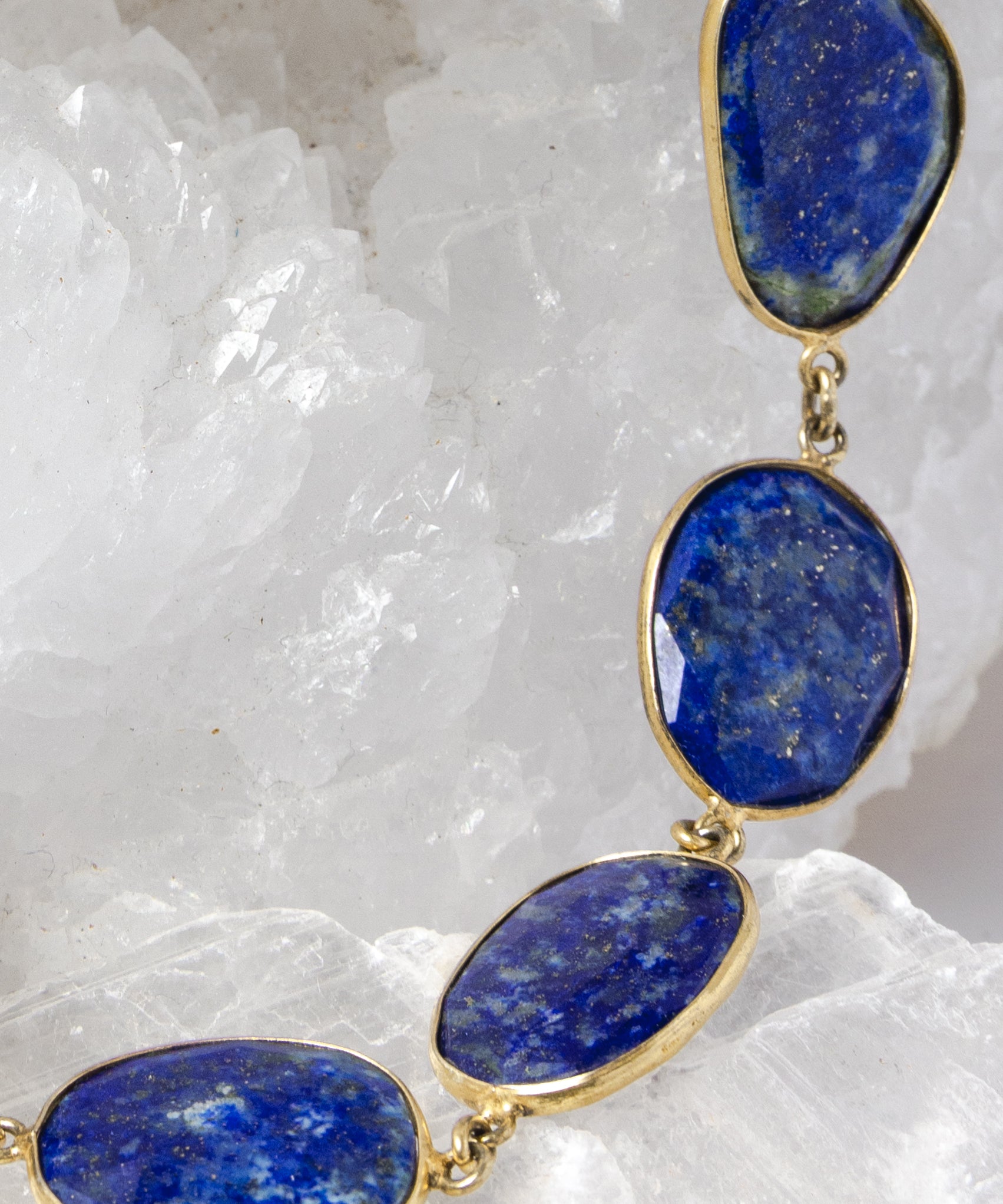 Close-up of faceted lapis lazuli gemstones showcasing rich royal-blue color, natural pyrite inclusions, and vermeil bezel settings.