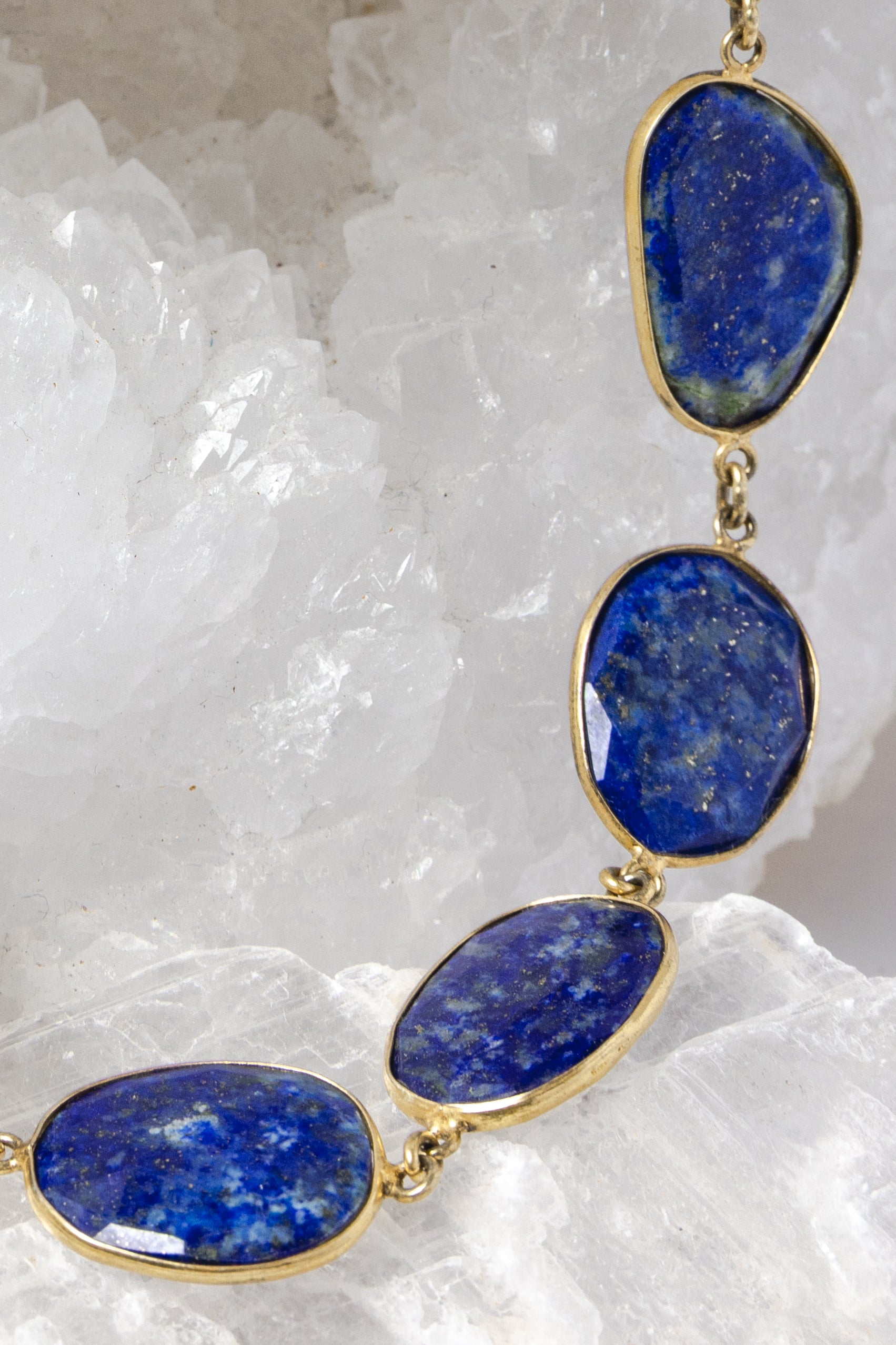 Close-up of faceted lapis lazuli gemstones showcasing rich royal-blue color, natural pyrite inclusions, and vermeil bezel settings.
