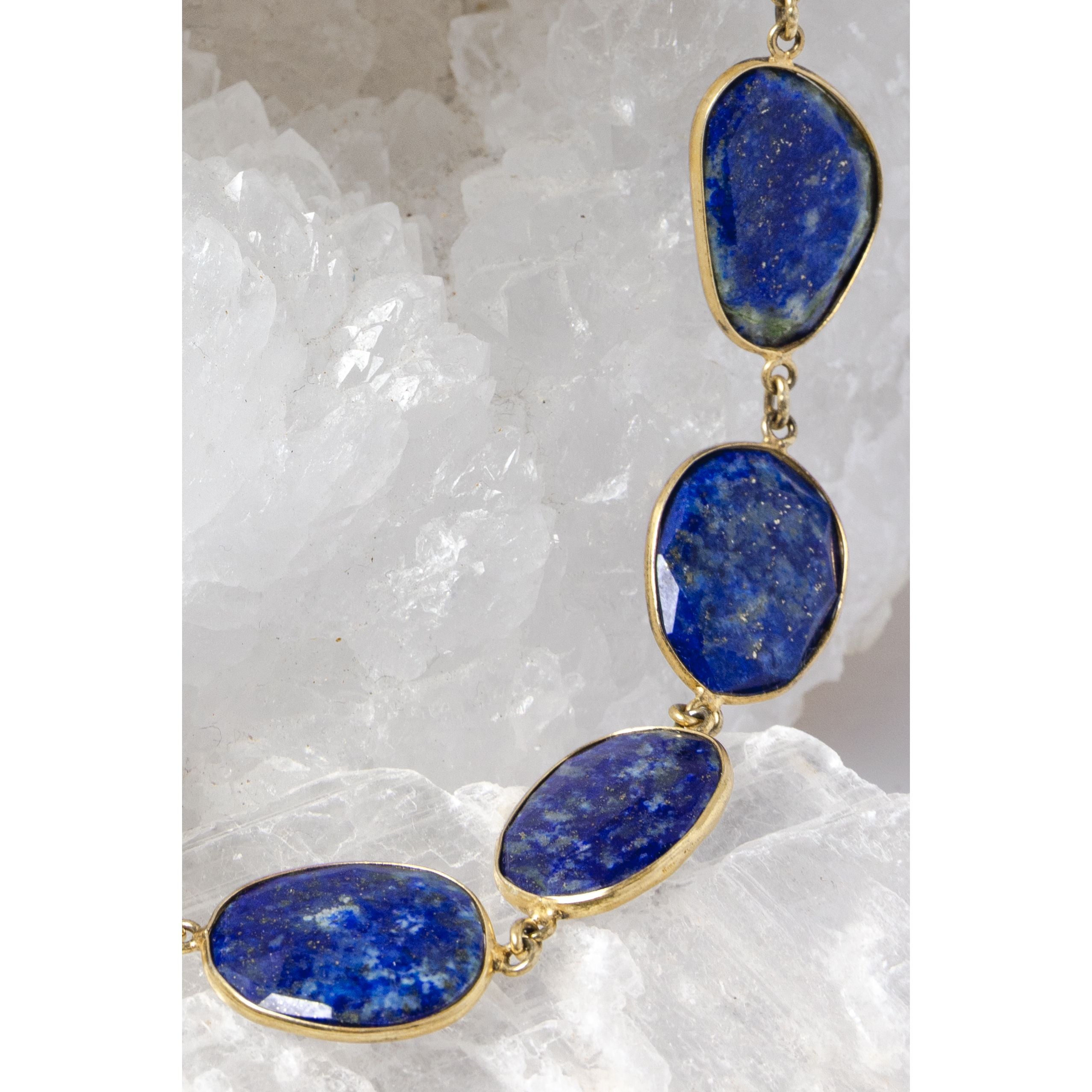 Close-up of faceted lapis lazuli gemstones showcasing rich royal-blue color, natural pyrite inclusions, and vermeil bezel settings.