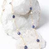 Blue Waltz long necklace featuring natural tanzanite gemstones and freshwater pearls arranged along a gold-plated chain with an elegant fluid silhouette.