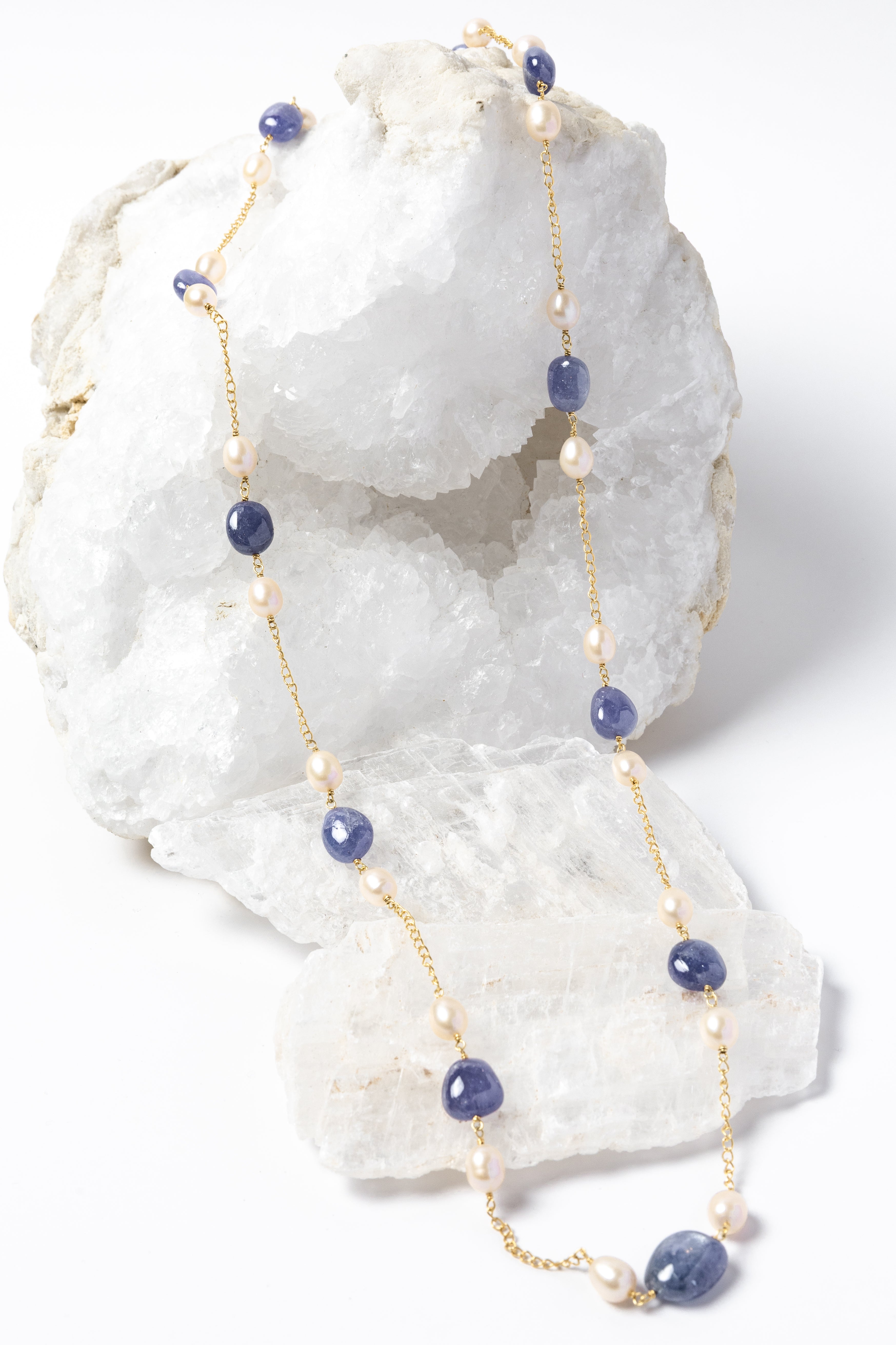 Blue Waltz long necklace featuring natural tanzanite gemstones and freshwater pearls arranged along a gold-plated chain with an elegant fluid silhouette.