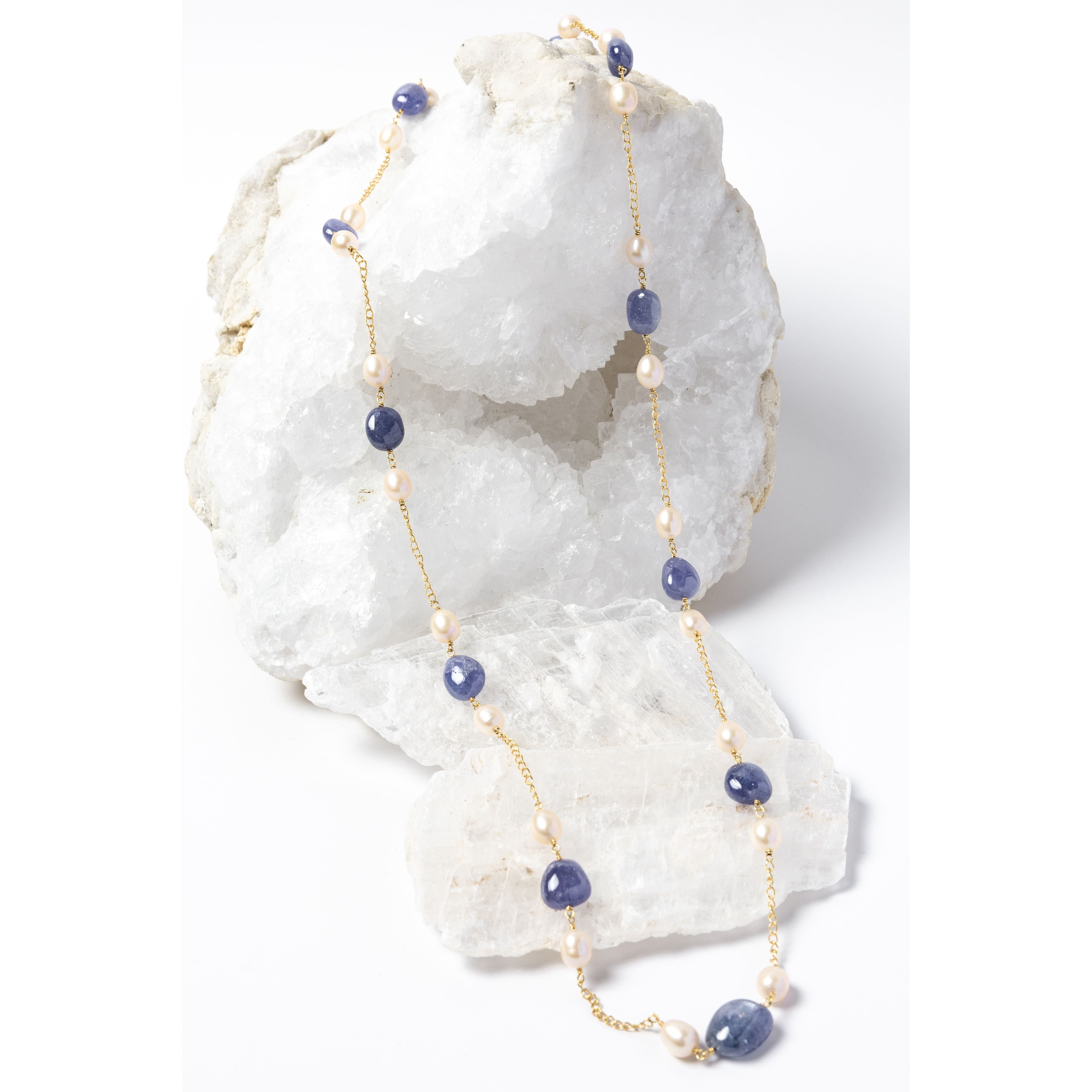Blue Waltz long necklace featuring natural tanzanite gemstones and freshwater pearls arranged along a gold-plated chain with an elegant fluid silhouette.