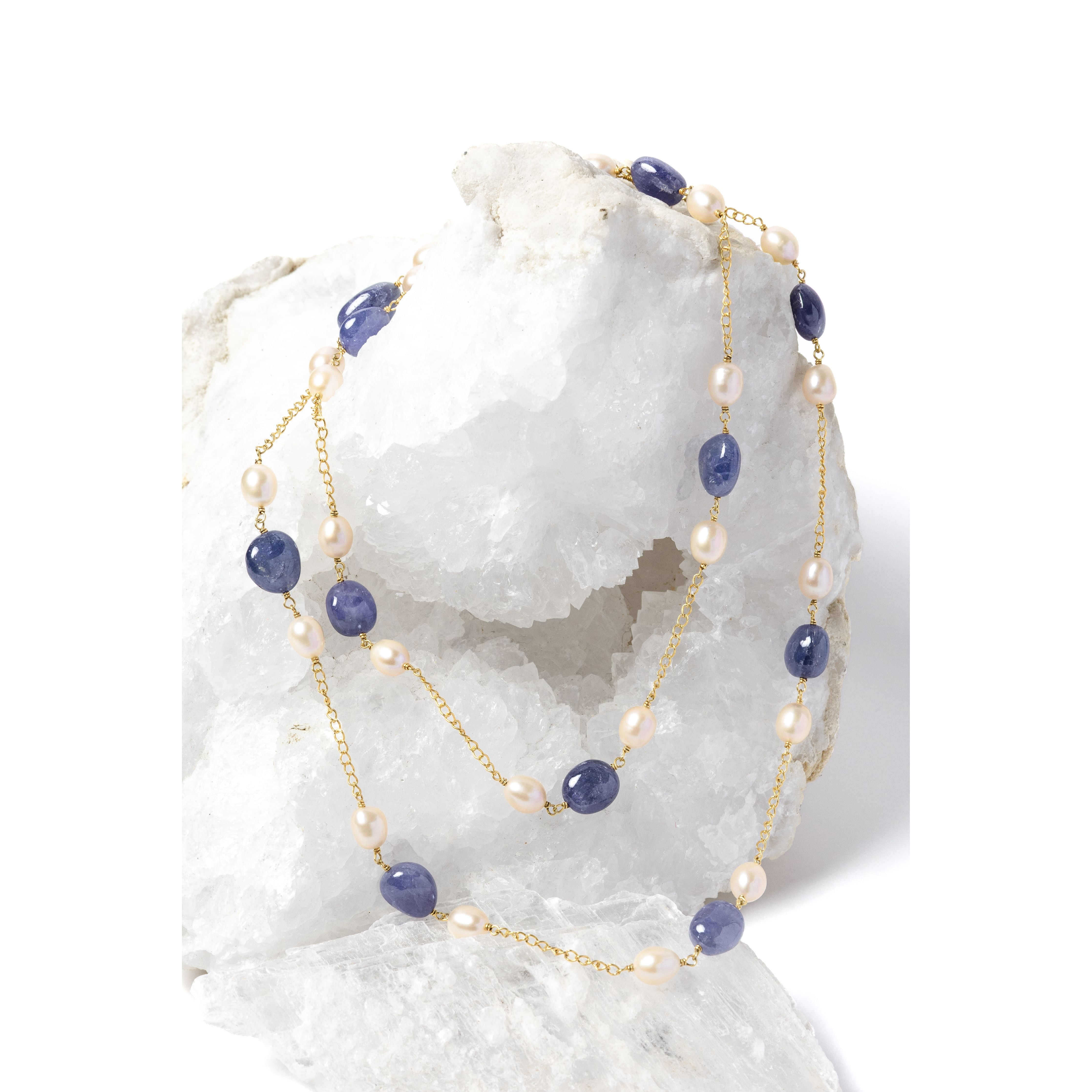 Blue Waltz necklace styled as a two-strand silhouette, showcasing rich blue tanzanites, luminous freshwater pearls, and a gold-plated chain.