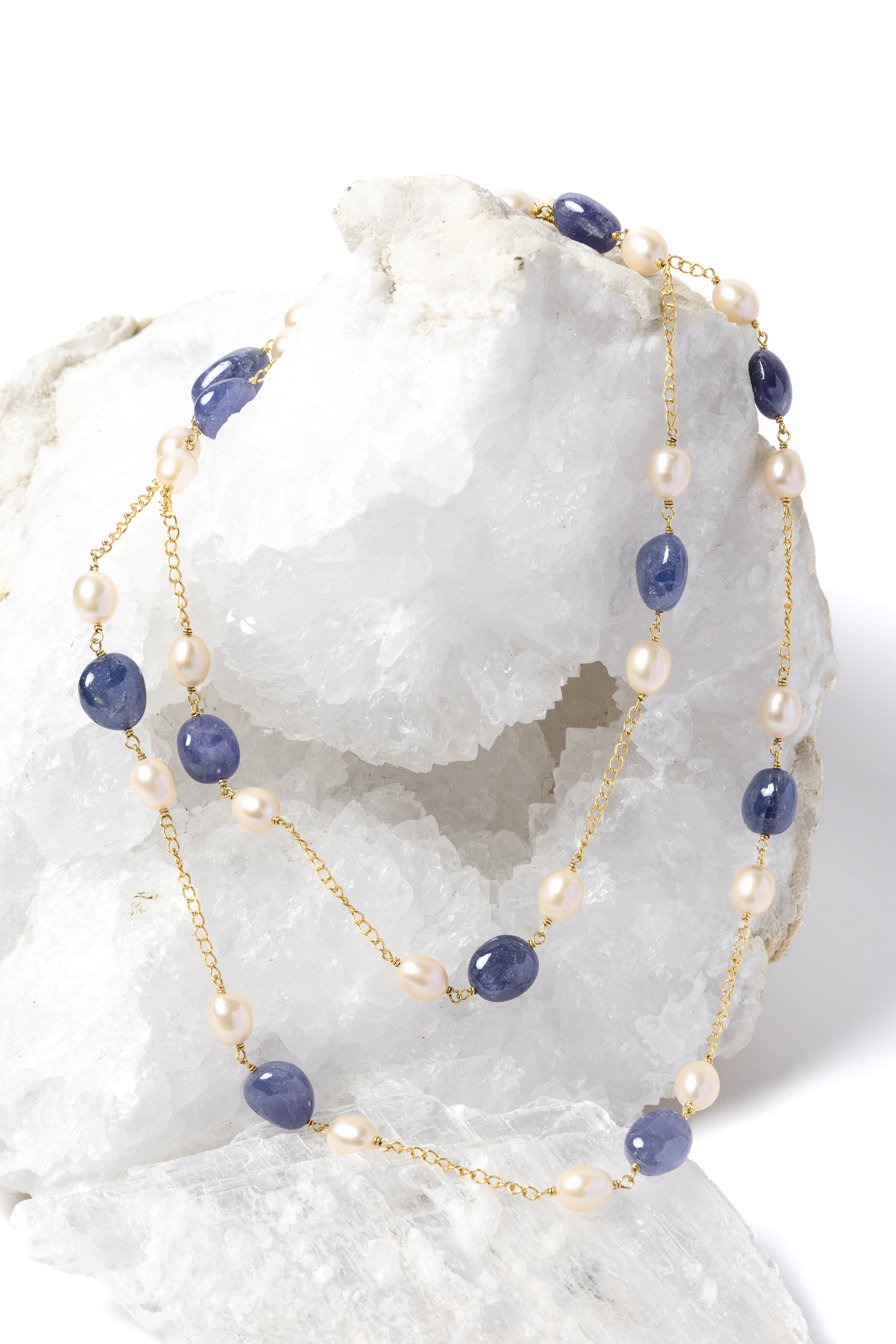 Blue Waltz necklace styled as a two-strand silhouette, showcasing rich blue tanzanites, luminous freshwater pearls, and a gold-plated chain.