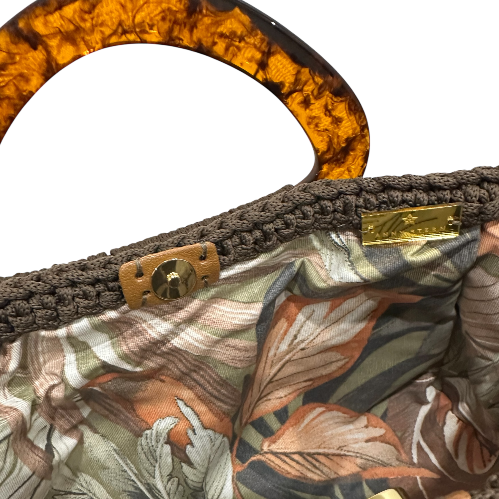Interior view of the Paloma handbag, revealing a botanical-patterned lining framed by the textured crochet structure and finished with refined resin handle details.
