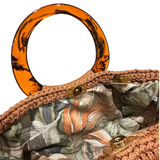 Hand-crocheted luxury handbag interior with botanical lining and spacious open design, featuring intricate crochet texture, sculptural resin handle and flowing tassel with chain detail