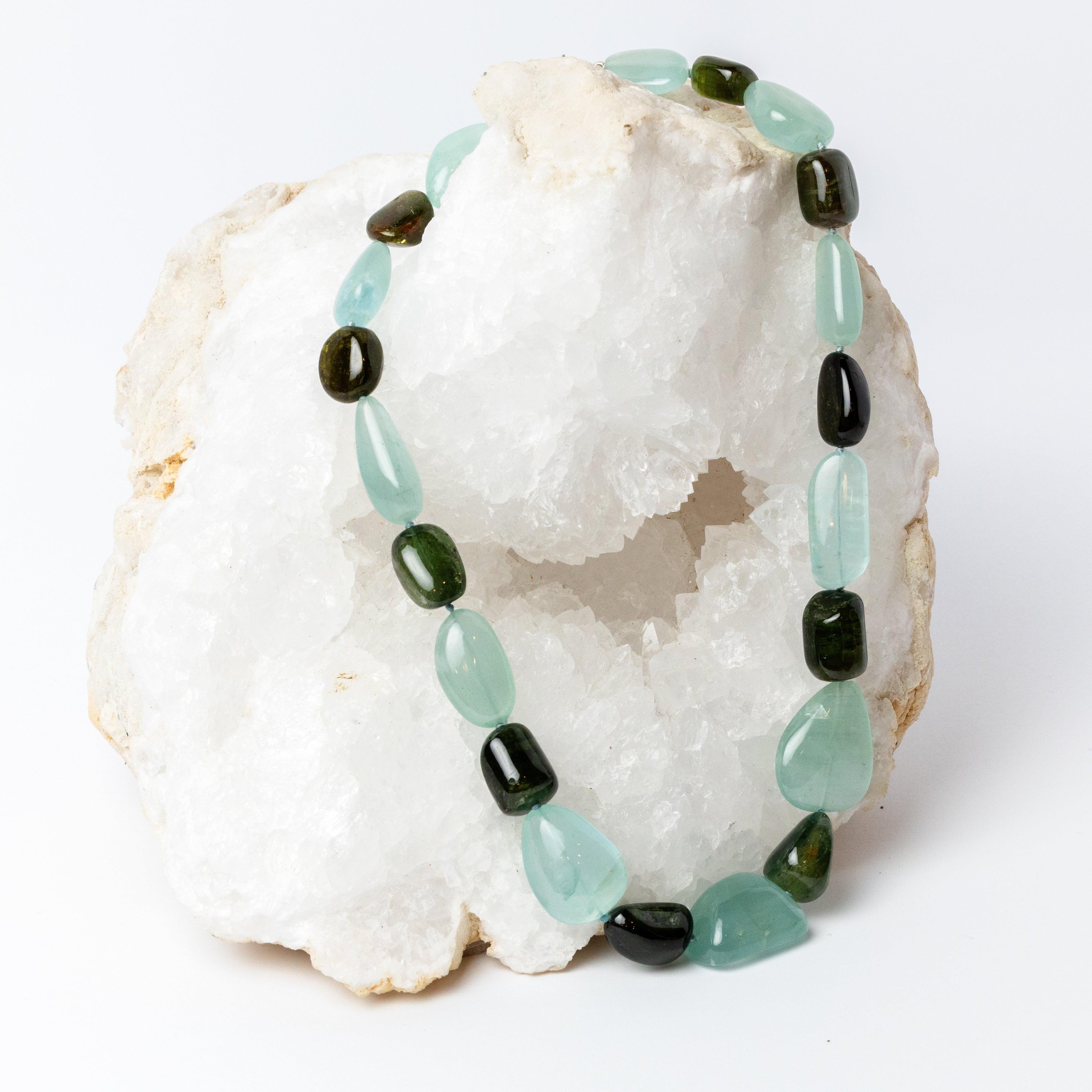 Deep Current Necklace featuring translucent aqua-blue aquamarine and polished natural tourmaline in deep green and smoky brown tones, arranged in alternating organic shapes and finished with a silver clasp.