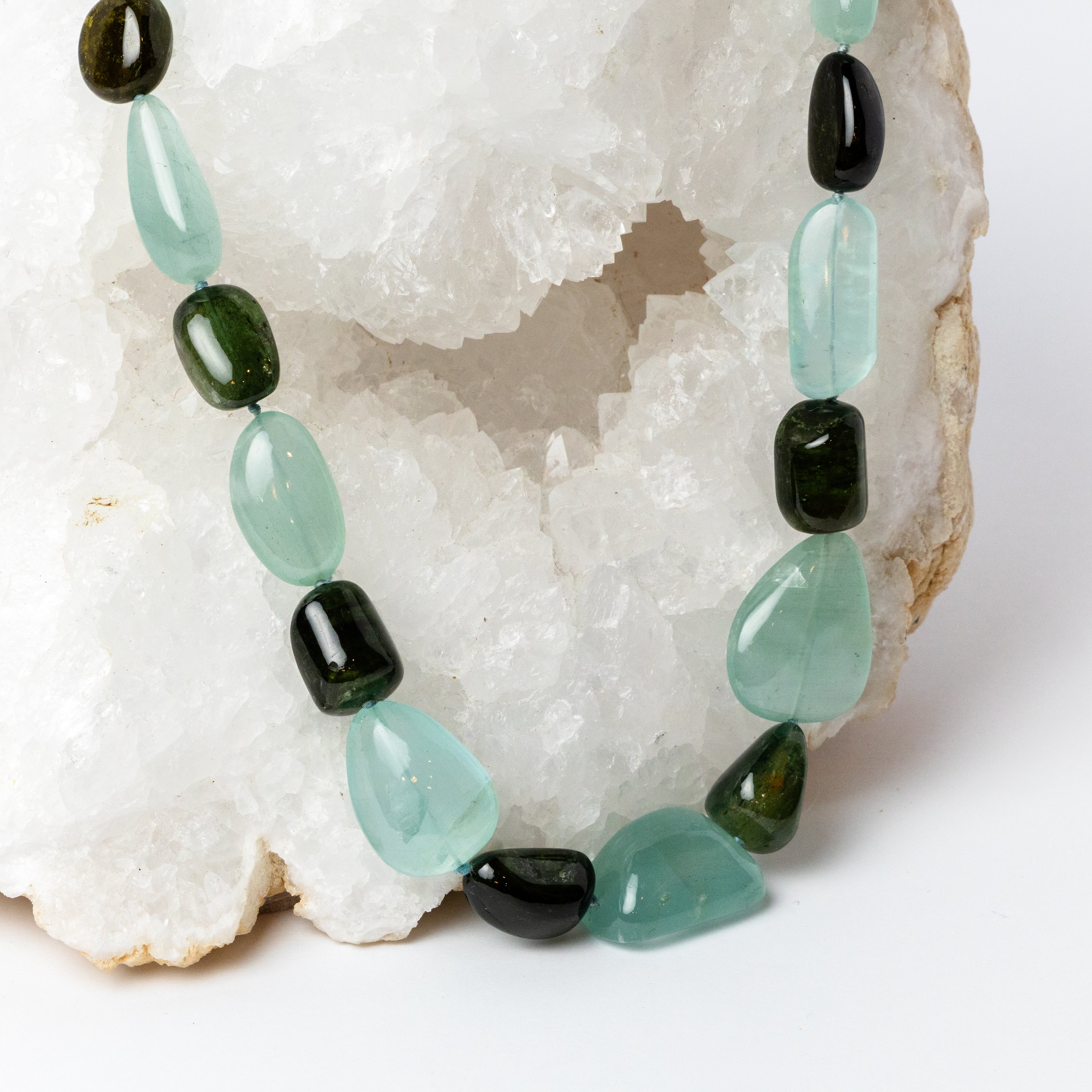 Close-up of Deep Current Necklace highlighting the translucent aqua-blue aquamarine and rich brown and deep green tourmaline gemstones, with their polished organic shapes, natural color variations, and beautiful contrast.