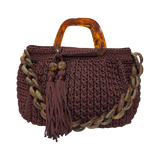 Hand-crocheted Giselle handbag in a deep bordeaux tone with dimensional vertical textured stitching, featuring marbled amber resin round handles, a coordinating chain strap, and tassel accents.