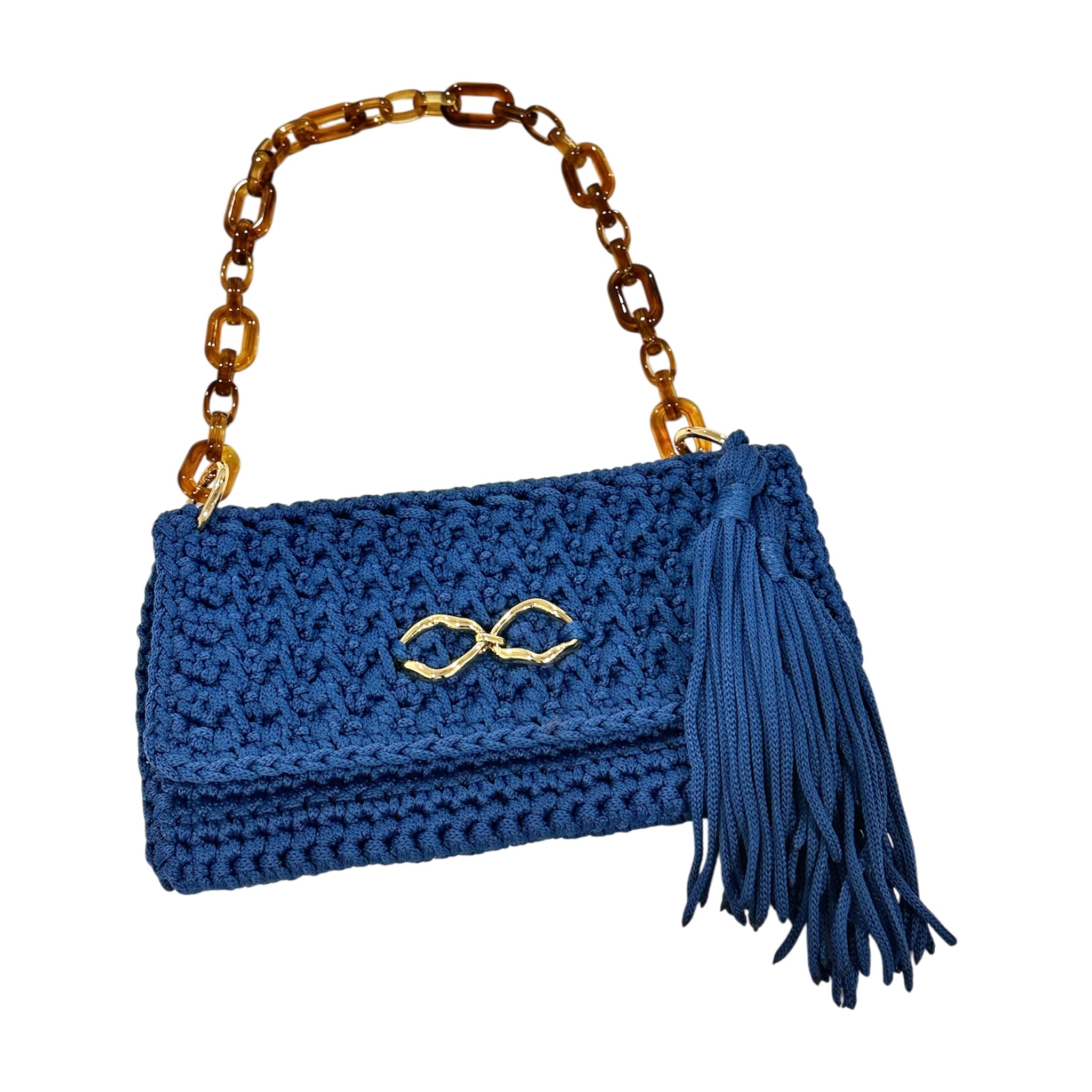 Handcrafted Polly Clutch in saturated royal blue featuring dimensional crochet texture, elongated tassel detail, polished gold-tone front accent, and sculptural tortoise-inspired resin chain strap with refined statement silhouette.