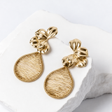 Angled view of Fiore d’Oro earrings highlighting the dimensional rounded flower petals and elongated hand-woven golden teardrops.