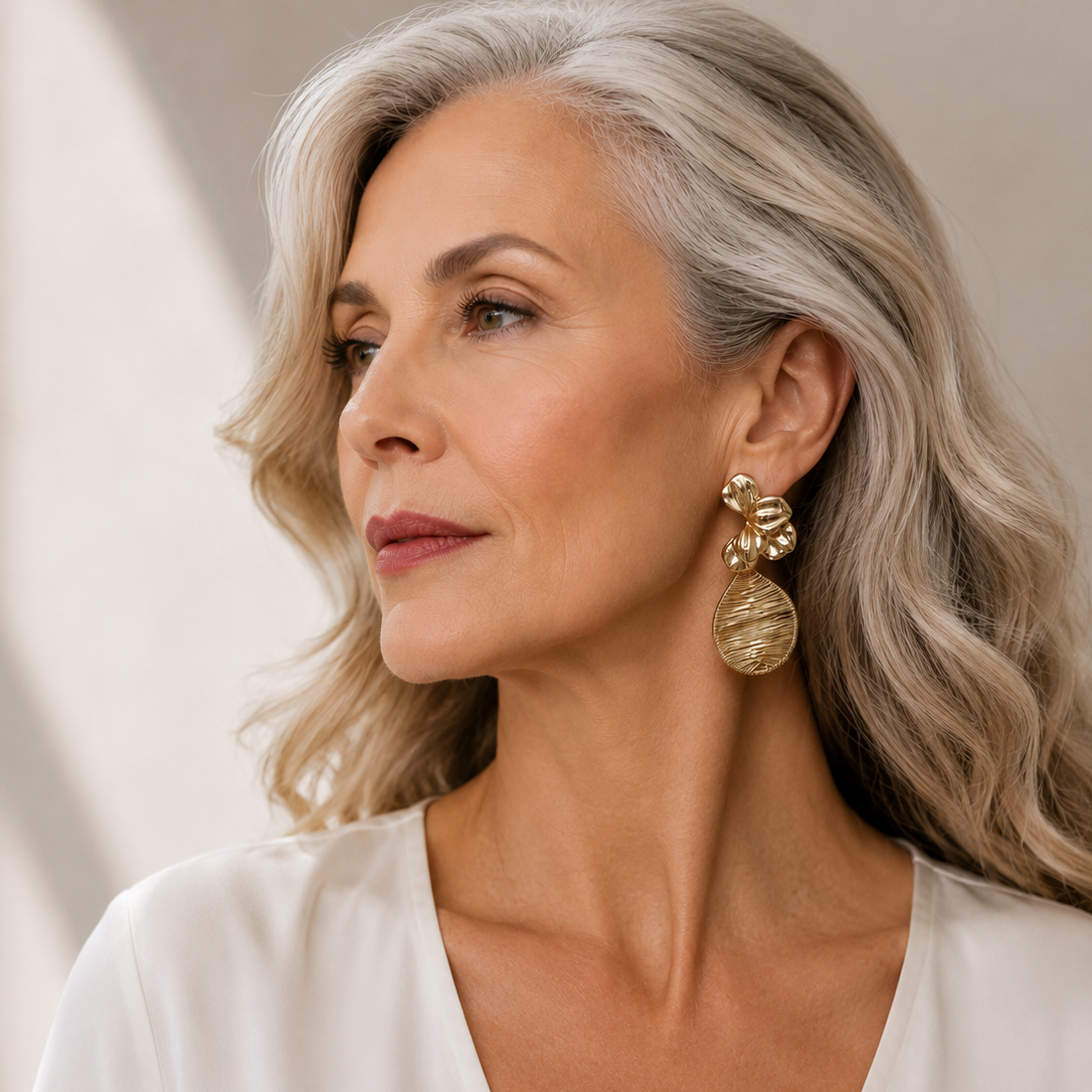 Fleur de Lumière gold-tone statement earrings featuring sculptural hammered floral details and intricate woven-wire teardrop pendants, approximately 3 inches long, worn by a model.