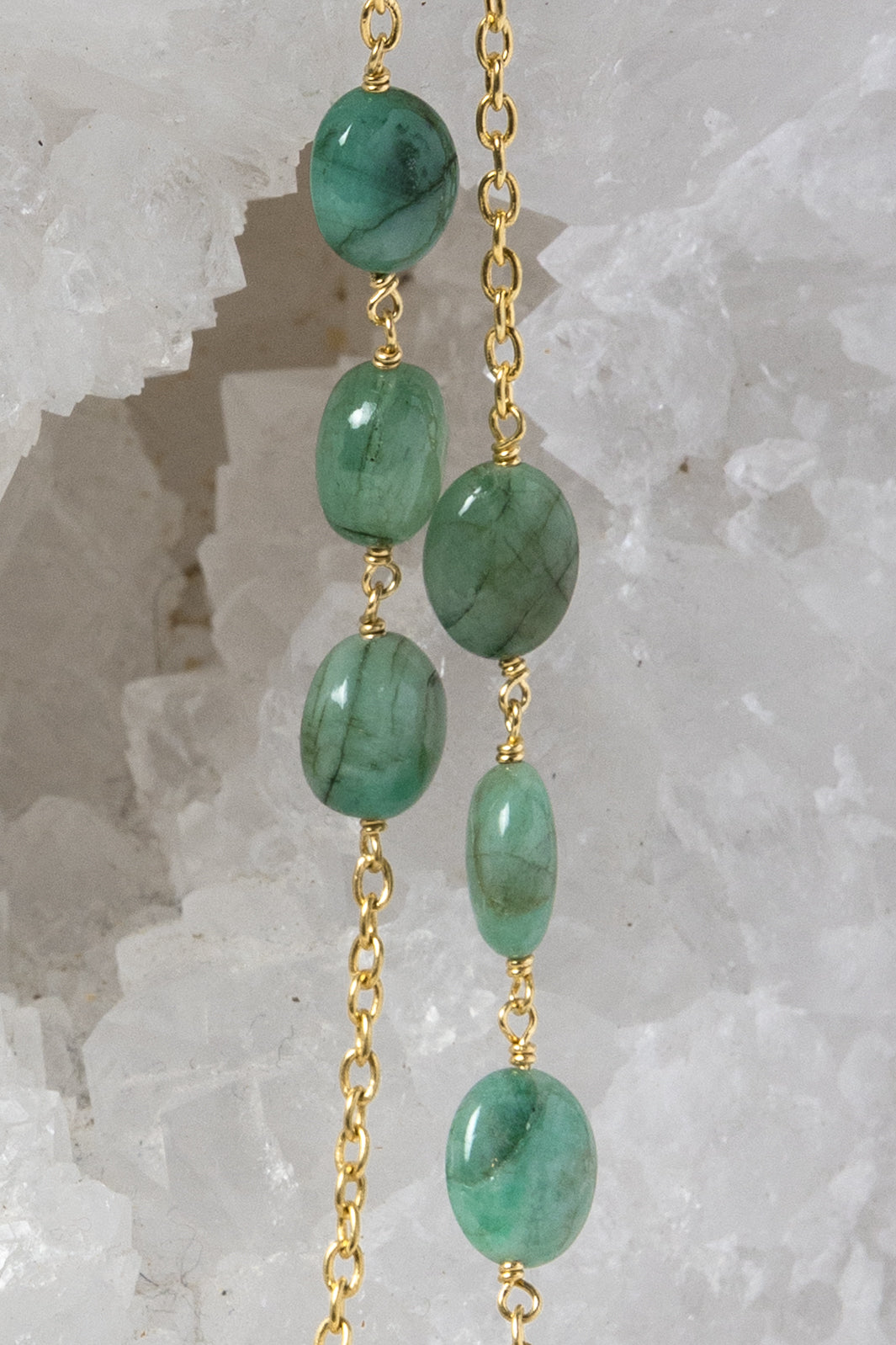 Close-up of the Fortuna Necklace highlighting natural emerald gemstones with rich creamy green tones, a distinctive velvety character, and gold-plated chain details.