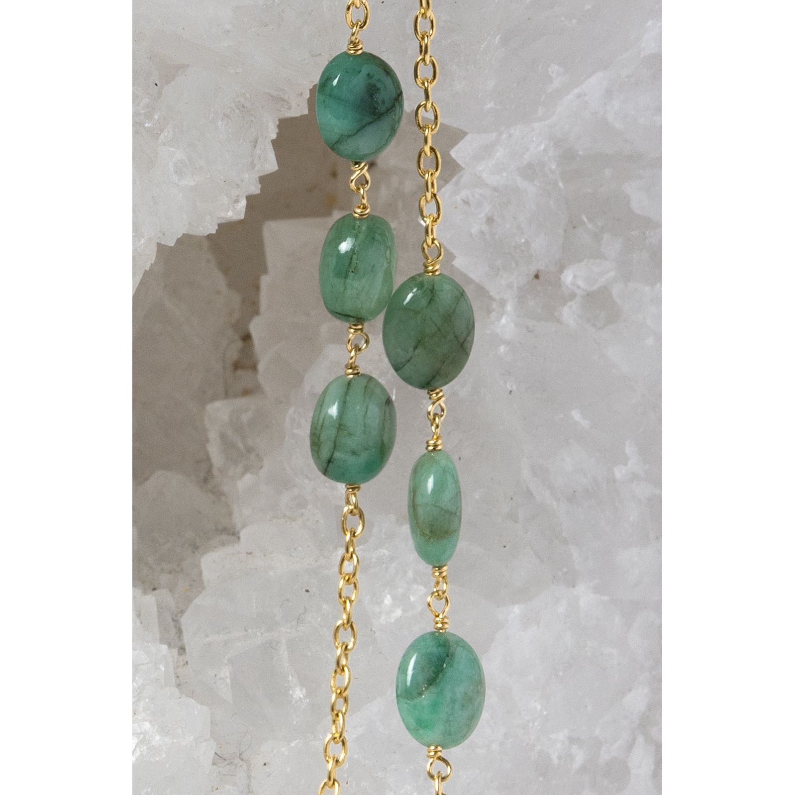 Close-up of the Fortuna Necklace highlighting natural emerald gemstones with rich creamy green tones, a distinctive velvety character, and gold-plated chain details.