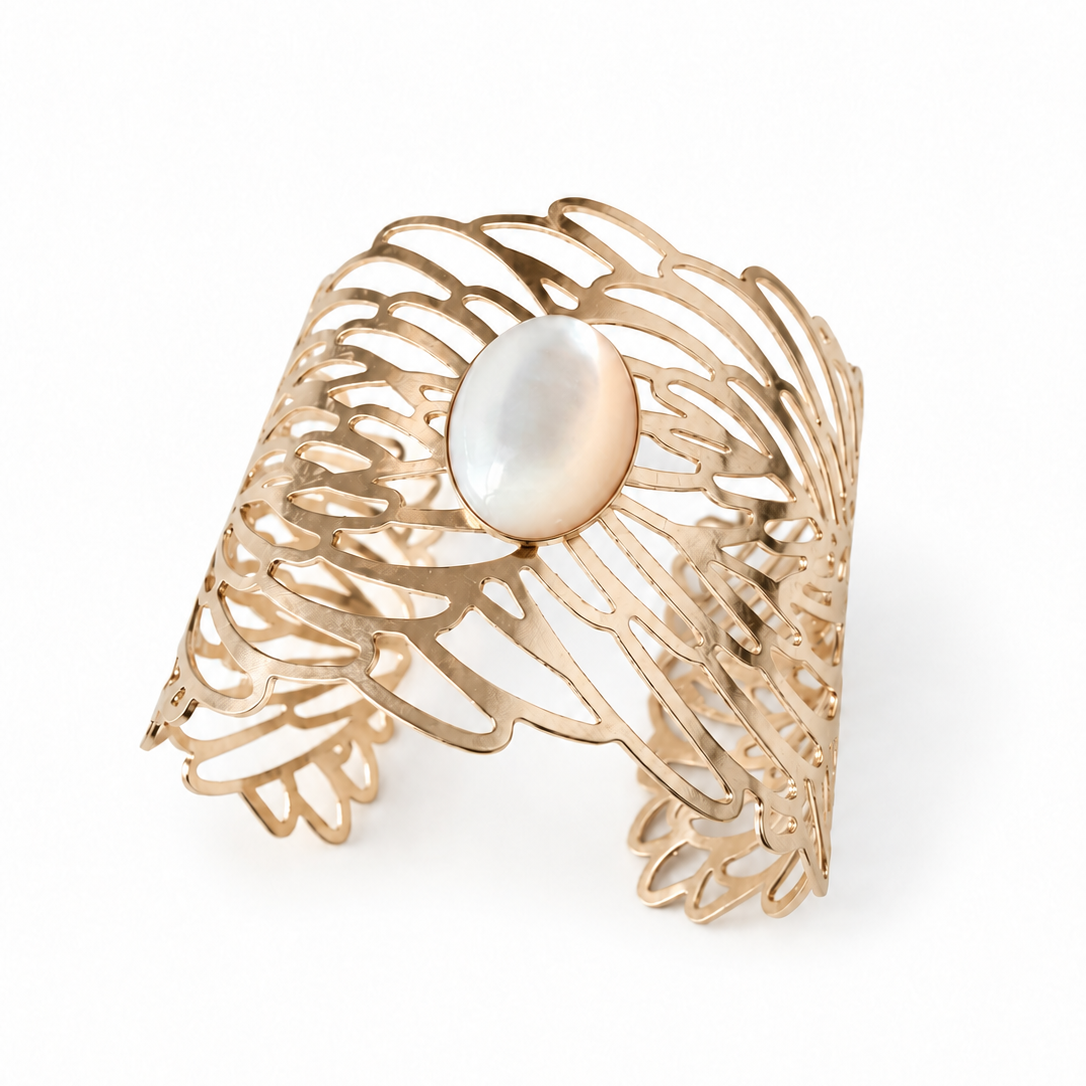 Golden Symphony Cuff featuring an 18 × 13 mm oval mother-of-pearl cabochon with luminous ivory tones, framed by sweeping golden curves and intricate sculptural openwork in a wide statement silhouette.
