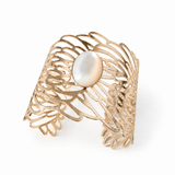 Golden Symphony Cuff featuring an 18 × 13 mm oval mother-of-pearl cabochon with luminous ivory tones, framed by sweeping golden curves and intricate sculptural openwork in a wide statement silhouette.